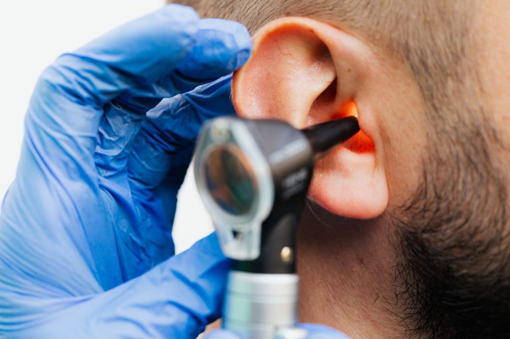 a-patient-having-ear-examination-5206951 Close-up of a doctor using an otoscope to examine a patients ear in a clinical setting.