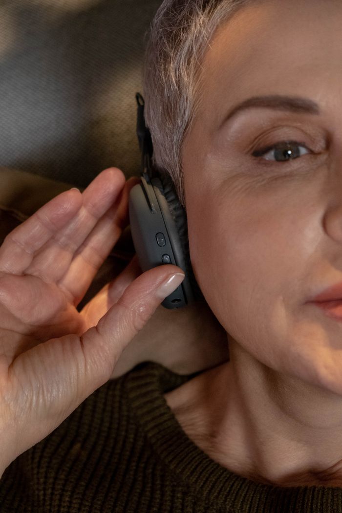 services-09 A relaxing close-up of a mature woman with headphones enjoying music indoors.